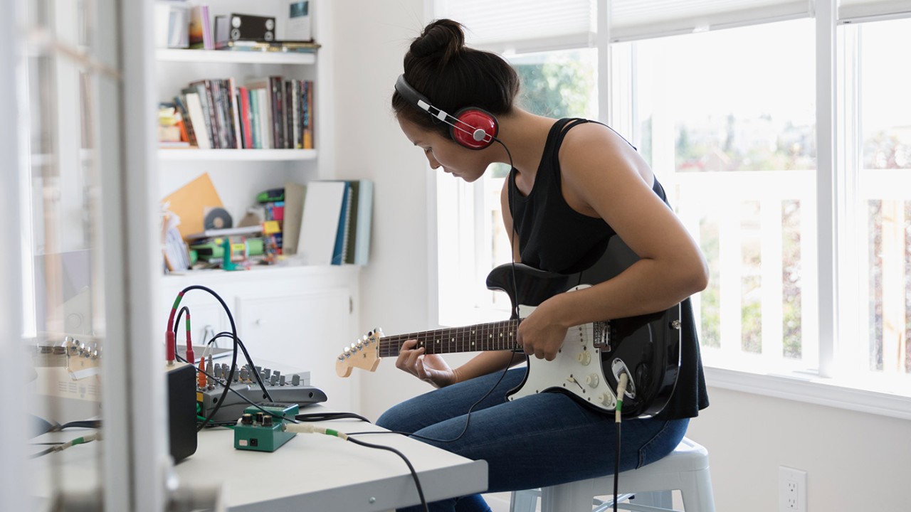 Woman listening to music and playing guitar; image used for HSBC Philippines Asset Link