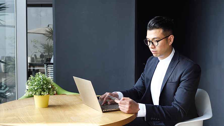 Man using his credit card and laptop; Image for 'What is credit score?' article