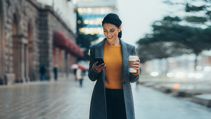 Woman holing her phone and coffee; Image for ' Credit card rewards' article