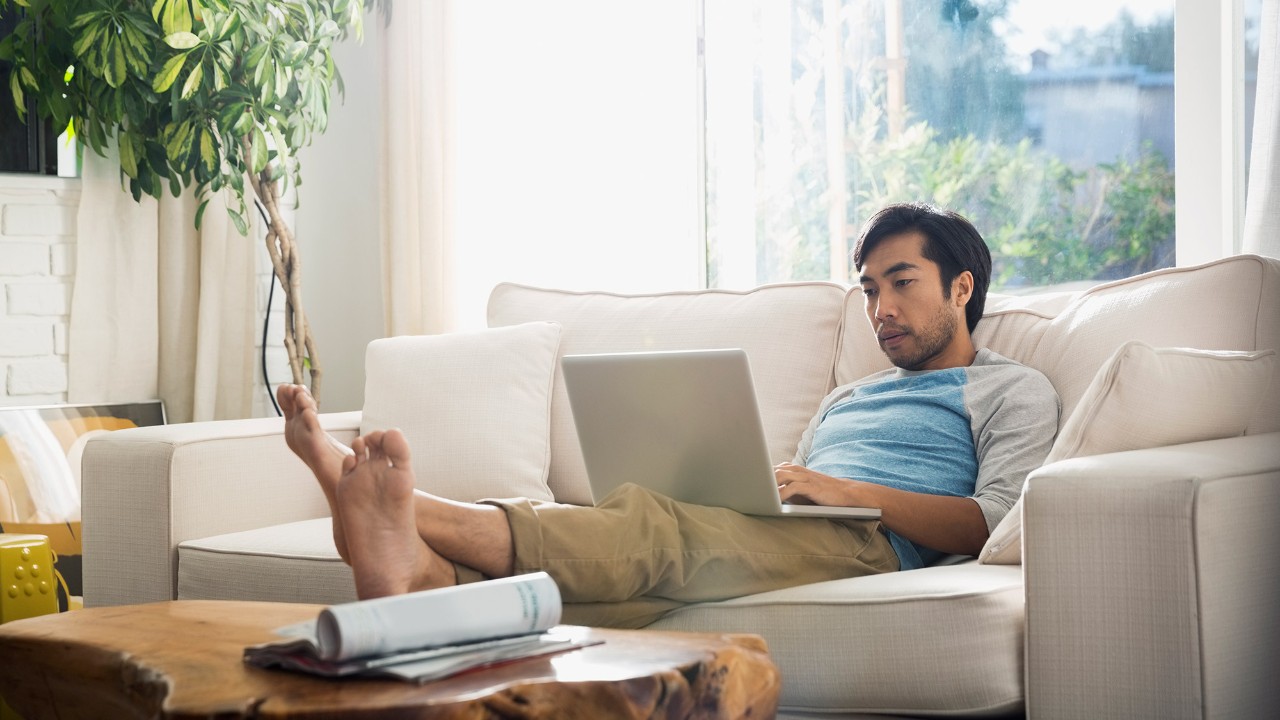 Beaded asian man using laptop at home; image used for HSBC Philippines Credit Cards Features eStatements page