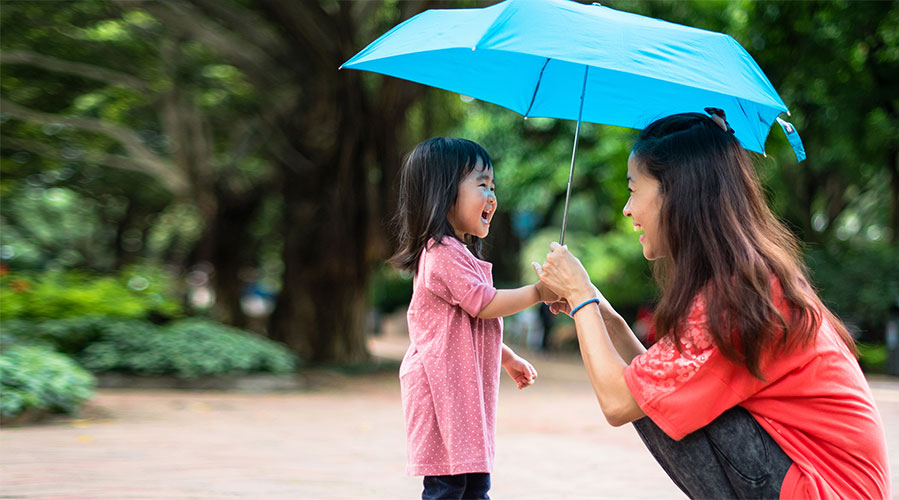 Mother and daughter under an umbrella; image used for HSBC Philippines COVID-19 security reminder page.