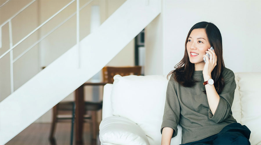 Woman on phone sitting on the couch; images used for HSBC Philippines Borrow ir Save article page.