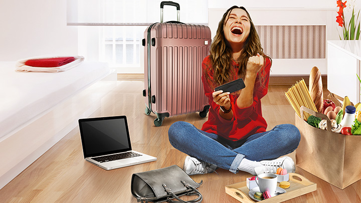 Woman sitting with credit card, laptop, grocery, suitcase, handbag; image used for HSBC Philippines Credit Card Offers Collect and Win page