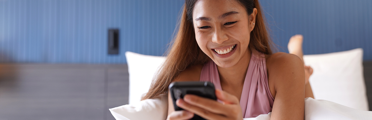 Woman using her phone while smiling; Image for Credit card application guide online