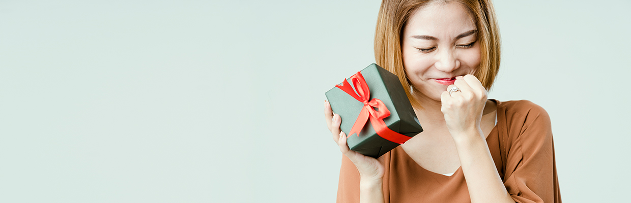 Woman excitedly holding a wrapped gift; image used for HSBC Philippines christmas 2020 promotion page