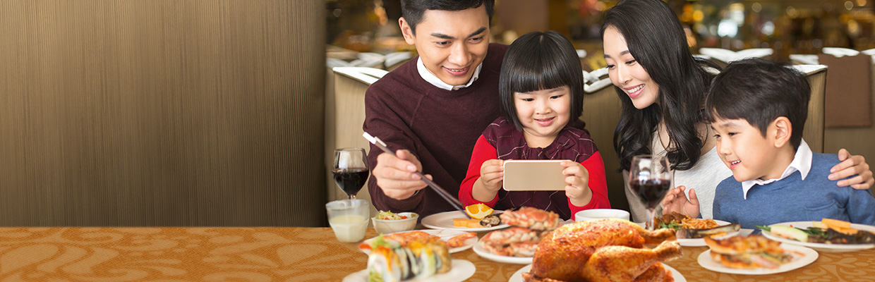 A family enjoys dinner with several foods; image used for HSBC Credit Cards Application Campaign