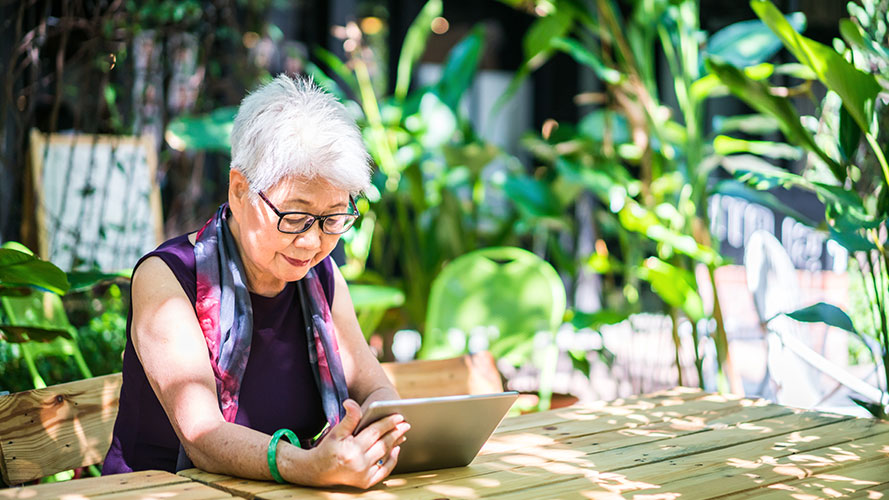 Older lady working on her iPad in her garden; image used for HSBC Philippines