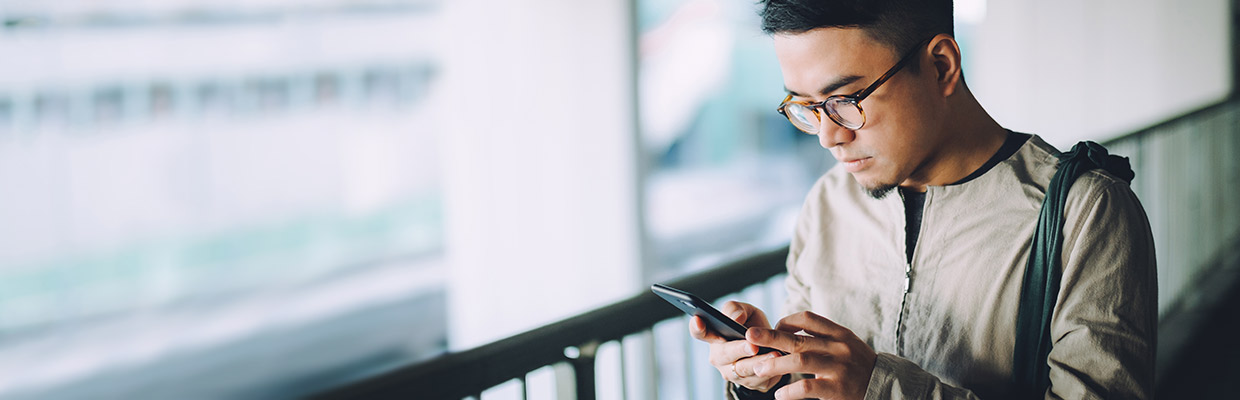 Man is looking at his mobile phone, image used for HSBC Mobile Banking Text Alerts.